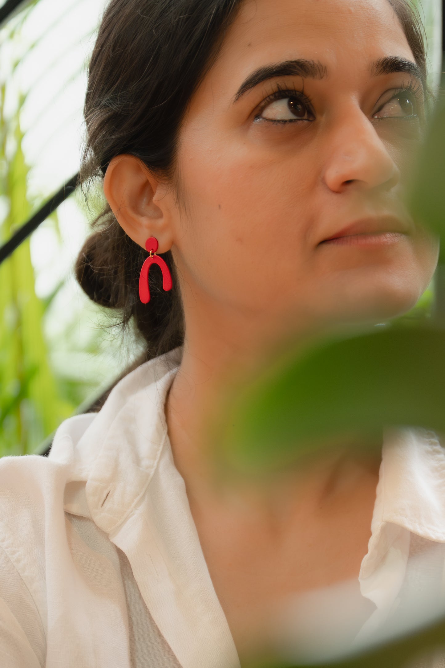 Woman wearing red earrings with a blurred natural background