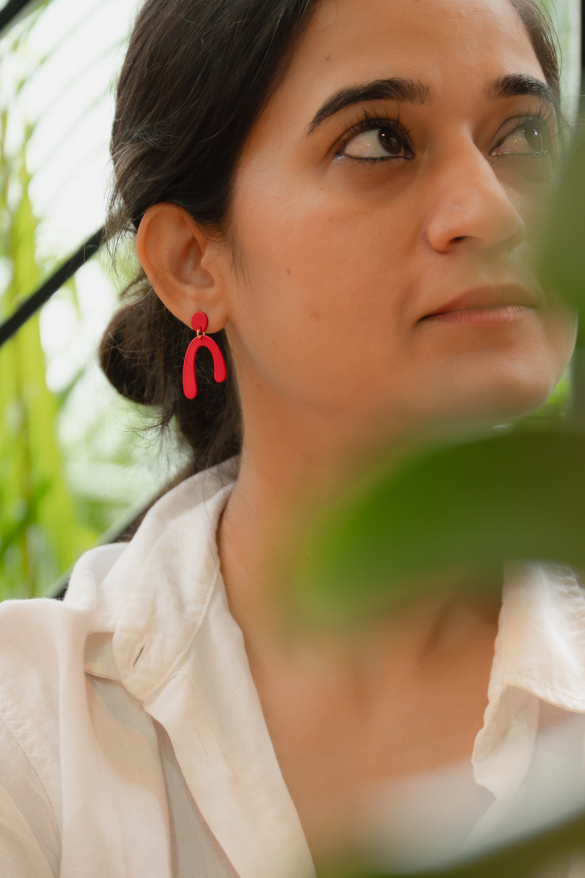 Woman wearing red earrings with a blurred natural background