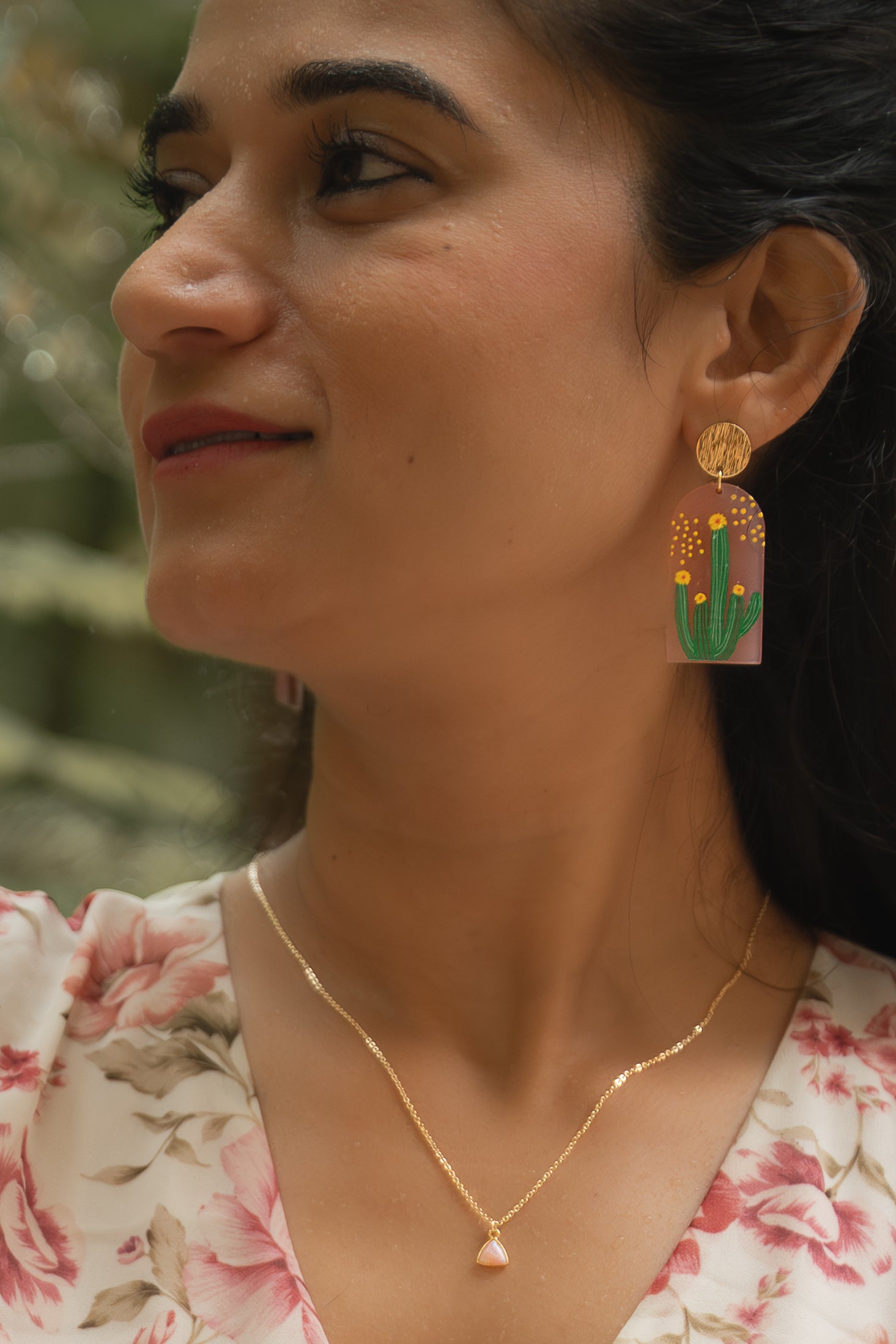 Close-up of a woman wearing colorful earrings with a blurred natural background