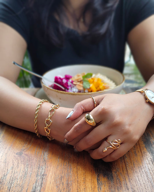 Close-up of hands with gold jewelry on a wooden surface
